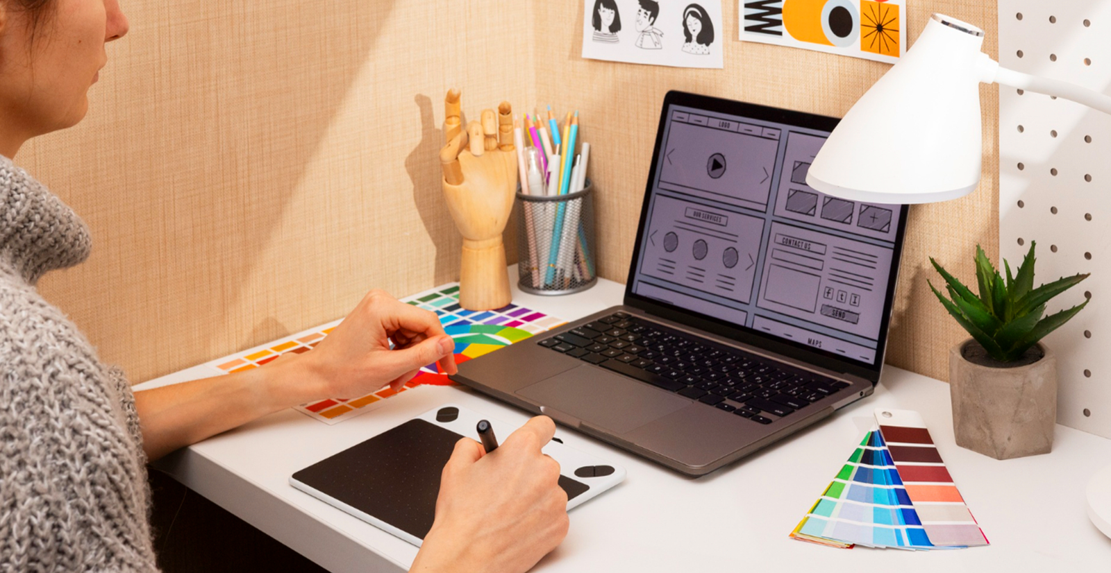 Seorang desainer kreatif bekerja dengan drawing tablet, laptop, dan color swatch untuk career switch ke industri kreatif